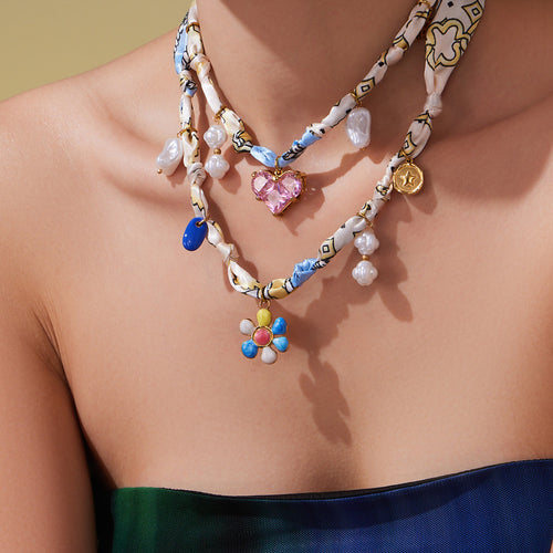 Model wearing stacked silk scarf necklaces with gold charms