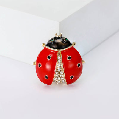 A rounded red ladybug with black spots and crystal-set center shown on a white background