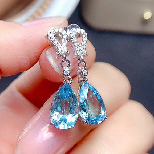 Pair of white gold light blue teardrop crystal earrings in hand