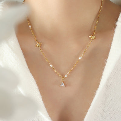 Model wearing gold star and triangle zircon pendant necklace with white top