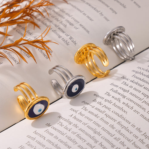 Gold and steel blue evil eye open rings on open book with dried plant