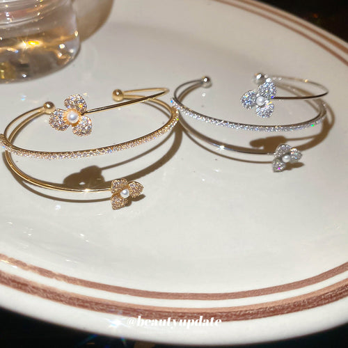 Gold and silver dual flower open bangles on white ceramic plate
