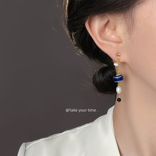 Model wearing blue ceramic disc pearl dangle earring on ear