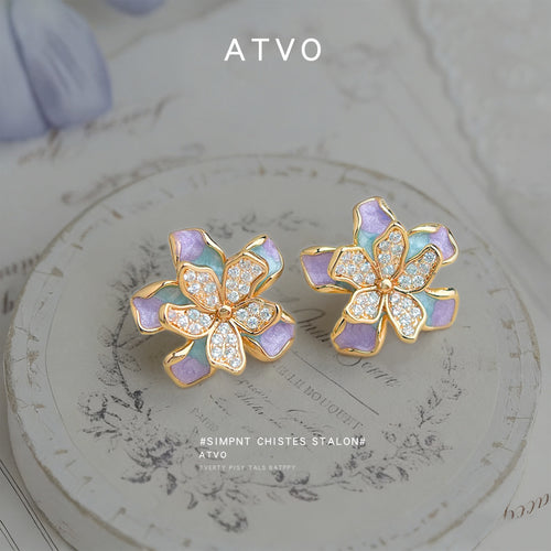 Gold-tone iridescent-lavender clear-stone flower studs in the first product display.