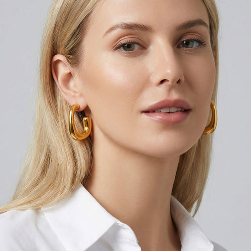 On-ear view of irregular rounded C hoop earrings in main image 2.