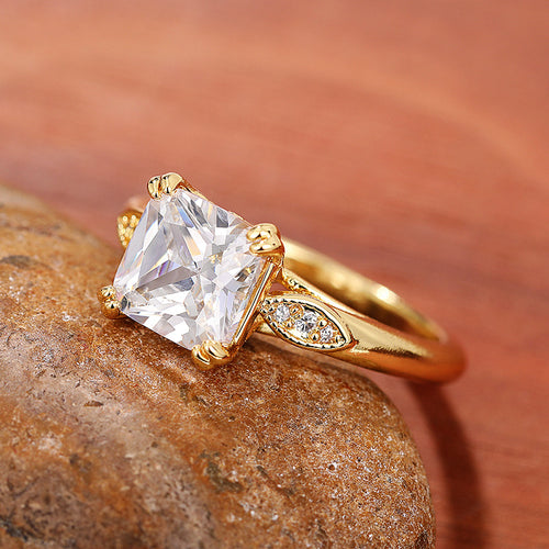 Gold square stone ring resting on brown rock wood background