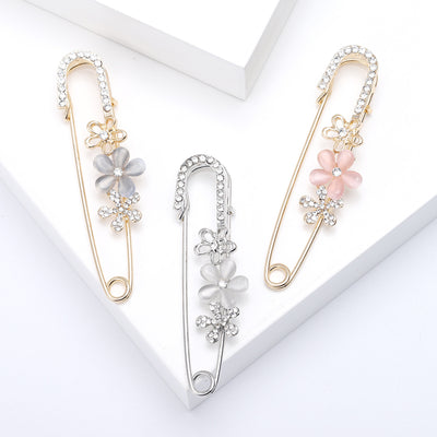 Three flower safety pin brooches in grey white and pink on white blocks