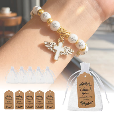 White cross bead bracelet with winged charm worn on wrist with bags tags