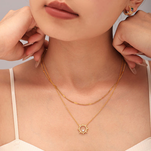 Model layering gold sunburst pendant necklace with flat side chain