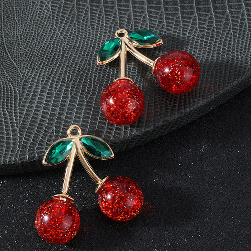Pair of glitter cherry pendants stacked diagonally showing gold-tone stems and green crystal leaves