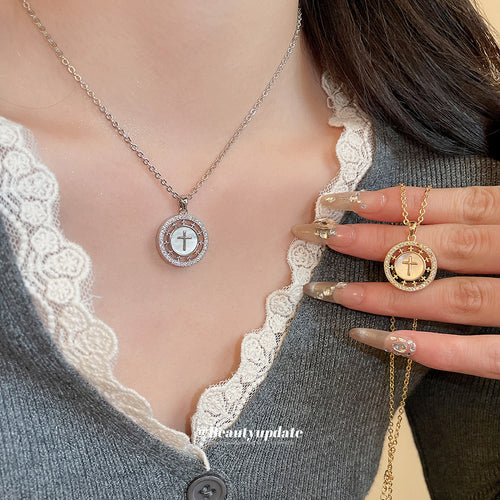 A round openwork medallion with a cross-like crystal motif on a fine chain shown in a front product view