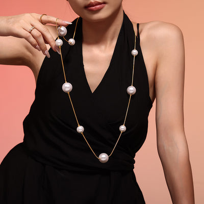 Gold long shell pearl station necklace on black dress