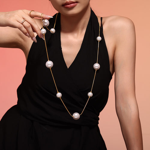 Gold long shell pearl station necklace on black dress