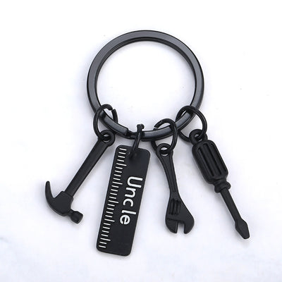 Black Uncle tag keychain with hammer, ruler, wrench and screwdriver charms on a white background.
