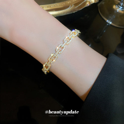 gold-tone open cuff with crystal-covered buckle-shaped links shown worn in a styled second view