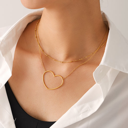Angled view of gold heart outline necklace and fine chain on white shirt