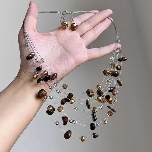 Multi-strand brown bead necklace and crystal earrings held in hand