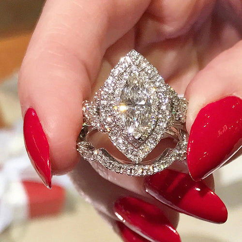 Silver marquise halo bridal ring set held with red nail polish