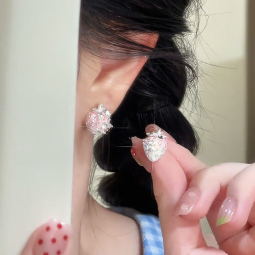 Styled view of pink strawberry stud earrings with crystal flower tops