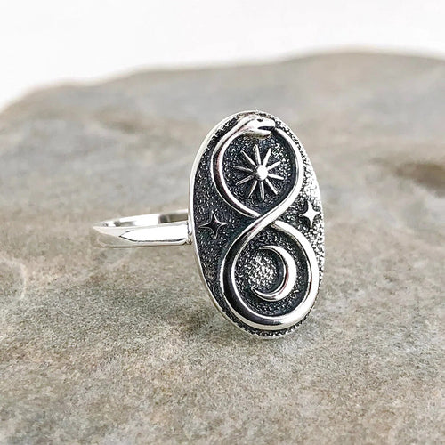 Side angle of antique silver snake sun moon oval ring on rock