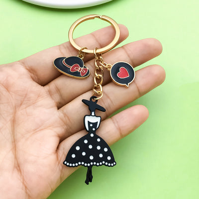 Image 1 showing a hand holding a keychain with a black and white dress.