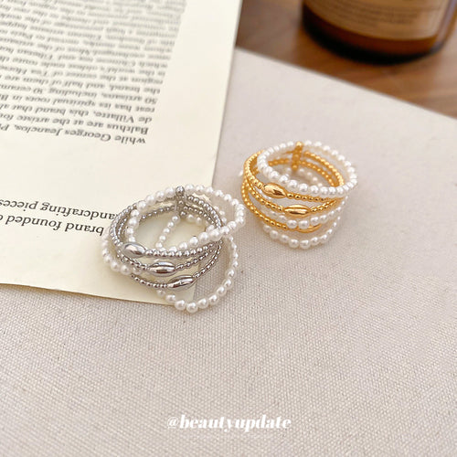 Silver and gold multi-layer pearl open rings on book and fabric