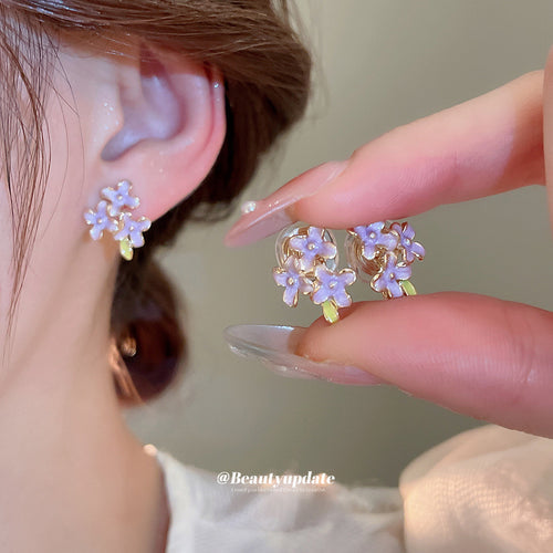 Purple Crystal Flower Earrings in Three Fastening Styles shown in a styled close-up