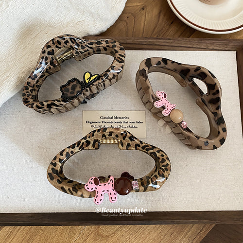 Three leopard acrylic claws with dog and heart charms on tray