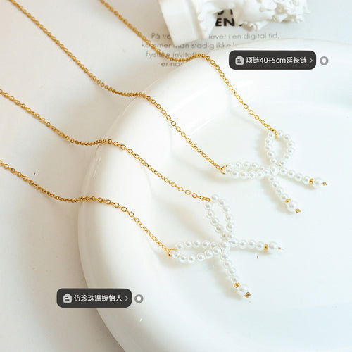 Two gold pearl bow necklaces on white dish with length and pearl tags