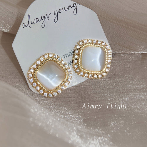 Gold-tone square white cat-eye clear-halo studs in the first product display.
