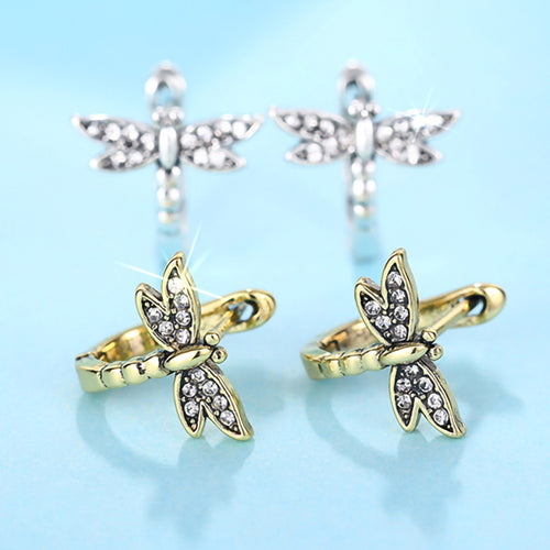 Gold and white metal dragonfly huggie pairs on blue background