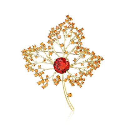 Gold maple leaf brooch with amber stones and red center on white