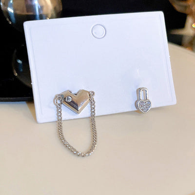 Front view of mismatched heart studs linked by a fine chain