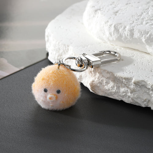 Yellow flocked pufferfish keychain with silver lobster clasp on dark surface