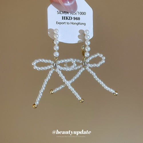 白色镶石蝴蝶结流苏耳环 shown worn for scale and shape