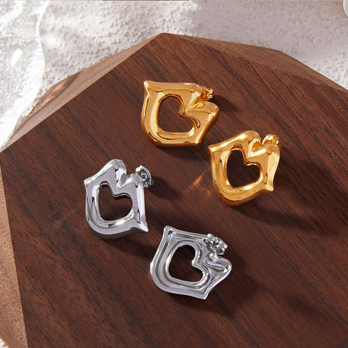 Gold and steel hollow heart lips studs on dark wood surface