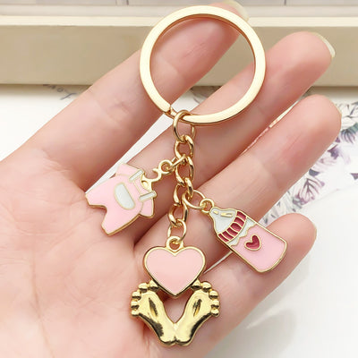 Overview showing the available color and design variations of the pink baby bottle outfit and footprint keychain
