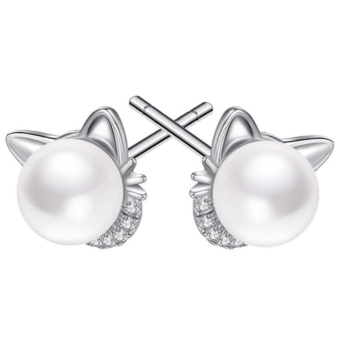 Silver cat ear pearl studs with posts crossed on white surface