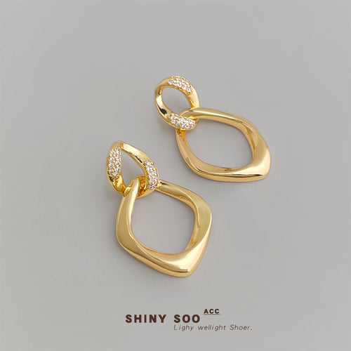 Gold dual geometric pave drop earrings on gray background