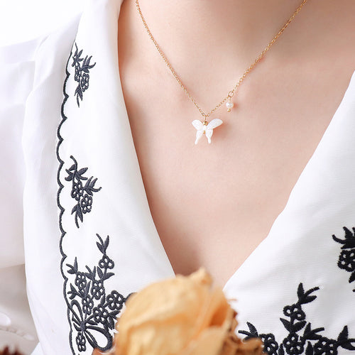 Shell butterfly pendant necklace worn on embroidered white blouse