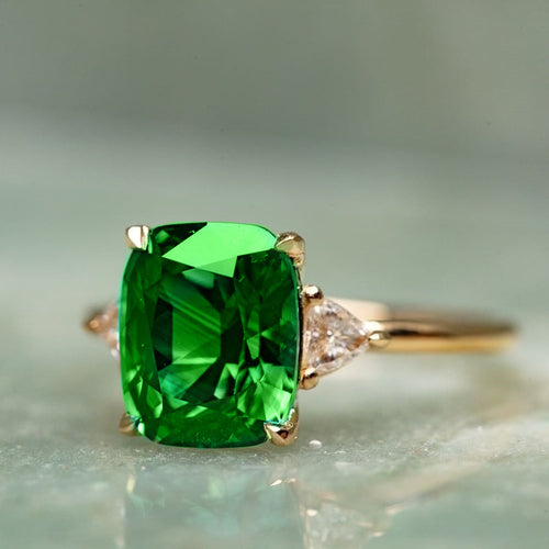 Second product view showing green cushion three-stone ring in gold and rose tones