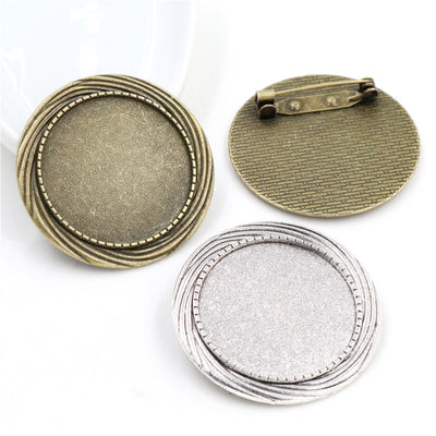 Overview of round bezel cups with horizontal pin backs in silver and antique bronze-tone finishes arranged on a light ba