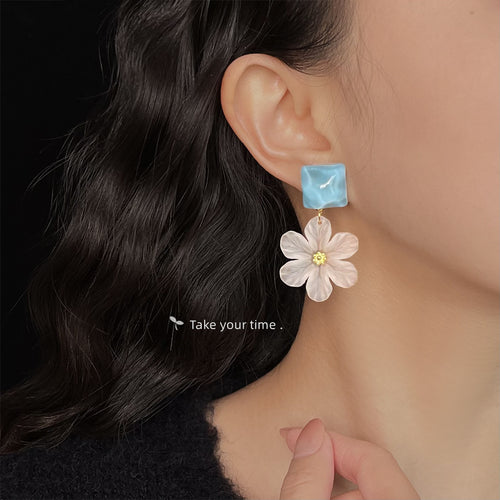 Aqua-square translucent-white-daisy drop studs shown worn on an ear.