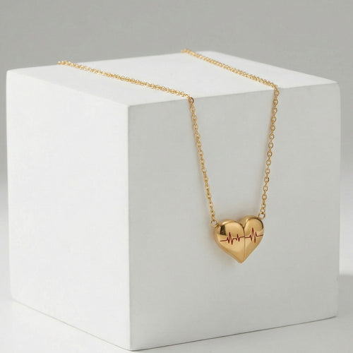 Gold heart ECG necklace draped on white display block