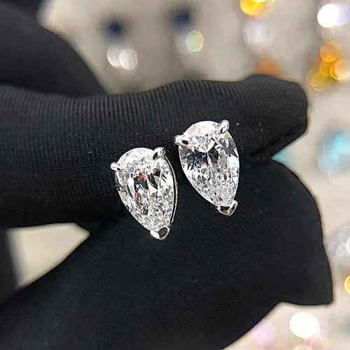 Pear CZ teardrop studs held on black gloved fingers