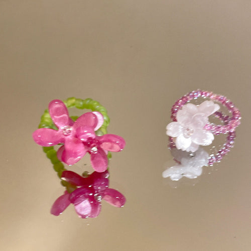 two resin flower beaded rings in pink, green, and white shown worn in a styled second view