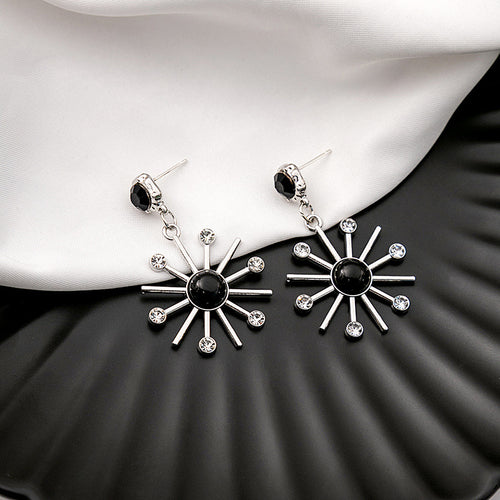 Black center silver sunburst starburst drop earrings on fabric
