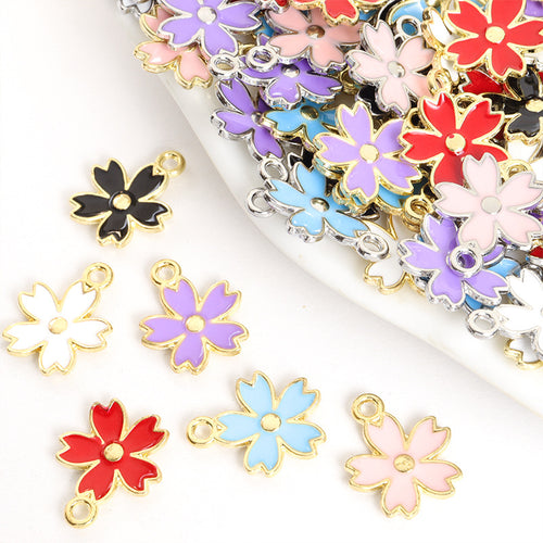 Assorted five petal enamel flower charms arranged beside a tray on white