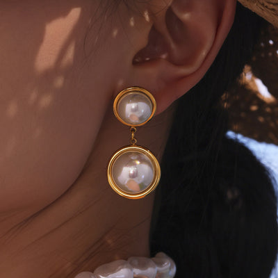 Gold double shell pearl drop earring worn on ear