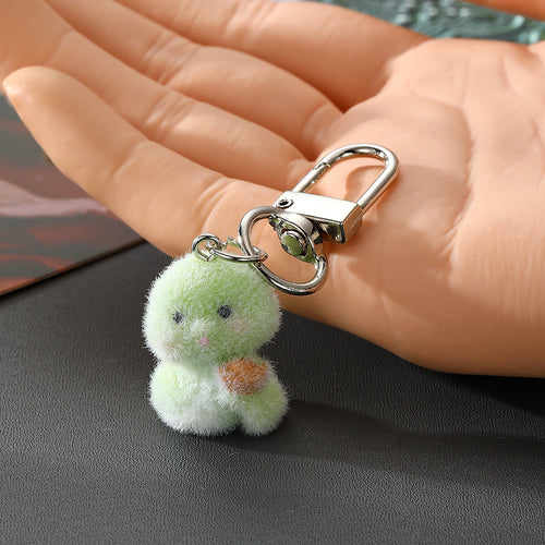 Green snake plush keychain holding gold ingot in hand for scale